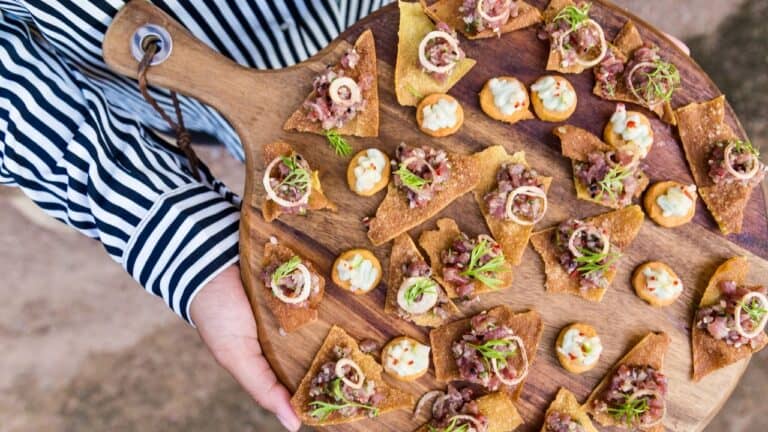 Grilled beef tacos with toppings on a wooden serving board, served at The Gourmet Host.