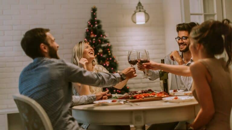 A festive dinner gathering with friends around a table, raising glasses in celebration.