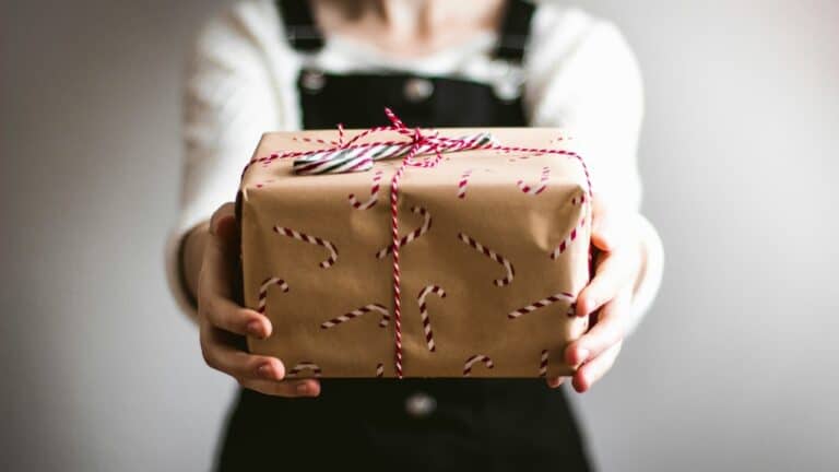 Woman holding a gift wrapped in brown paper with candy cane ribbon.
