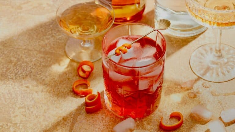 A lush assortment of colorful cocktails and drinks on a sandy surface, perfect for a summer party.