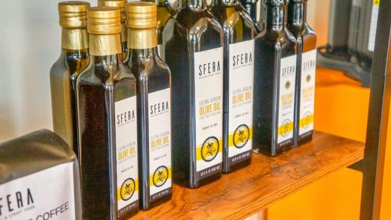 Premium extra virgin olive oil bottles displayed on a wooden shelf at The Gourmet Host.