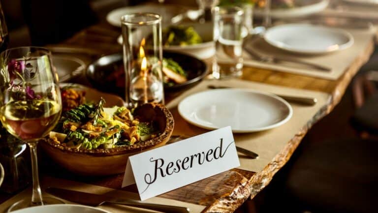 Elegant dining table set with reserved sign, wine glasses, candles, and gourmet dishes for a fine di.