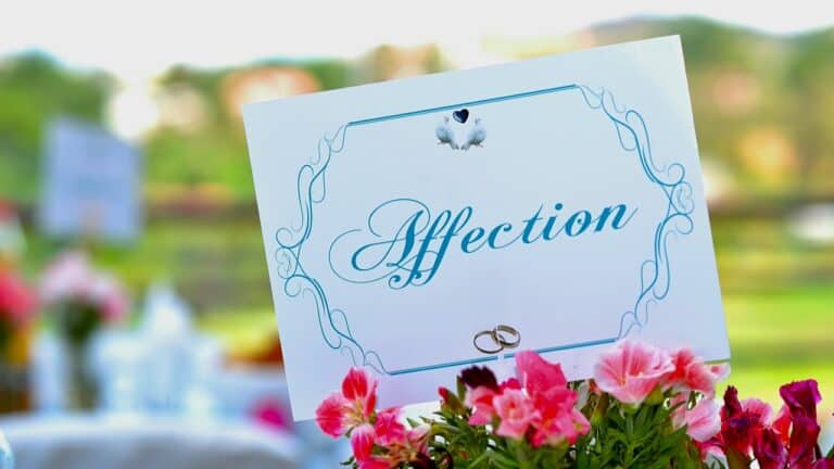 Close-up of a wedding invitation with pink flowers and wedding rings.