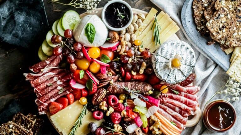 A delicious assorted charcuterie and cheese platter with fresh fruits and nuts.