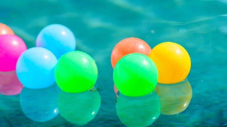 Colorful floating pool balls on water for summer pool party fun.
