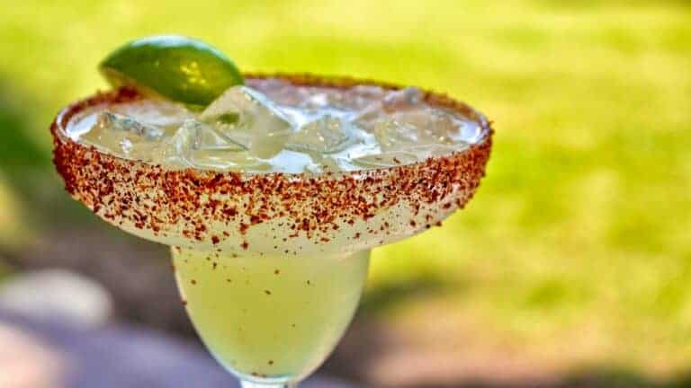 A colorful Shirley Temple mocktail garnished with lime and served in a salted rim glass.