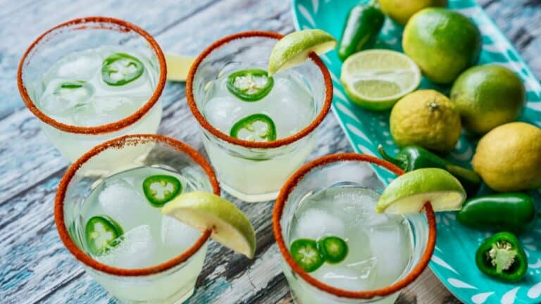 Refreshing lime and jalapeño cocktails with salted rims, served in glasses with lime wedges.