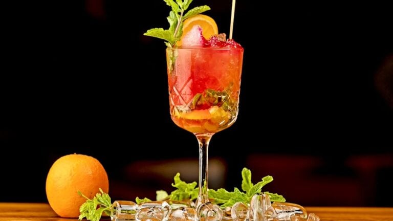 A refreshing Shirley Temple mocktail garnished with fruit and mint in a tall glass.