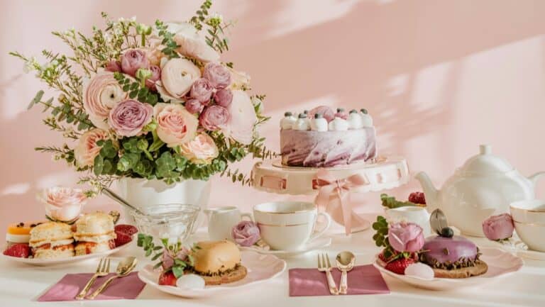 Elegant floral table setting with pastel desserts and tea accessories for a sophisticated event.