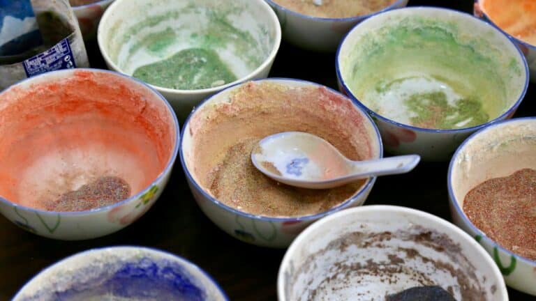A variety of colorful spice bowls with different ground spices and herbs for cooking.