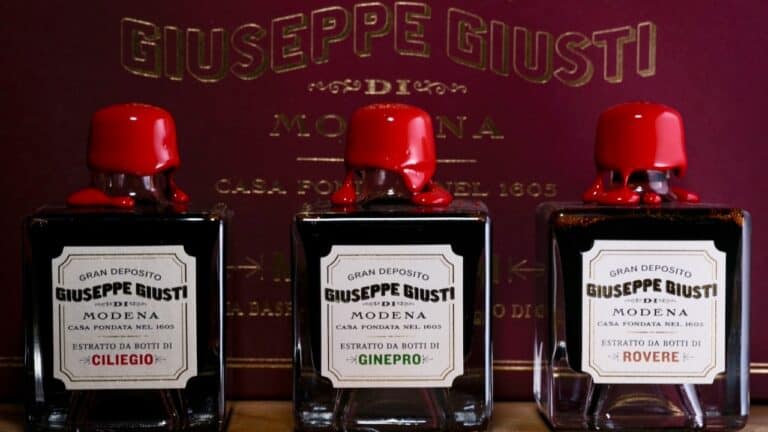 Aromatic Italian balsamic vinegar bottles with red caps, displayed in front of a branded box.