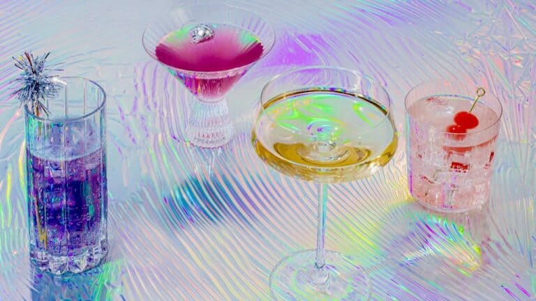 A colorful assortment of cocktails with vibrant garnishes on a holographic surface.