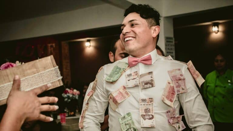 Happy man at engagement party with money decorations and guests in background.
