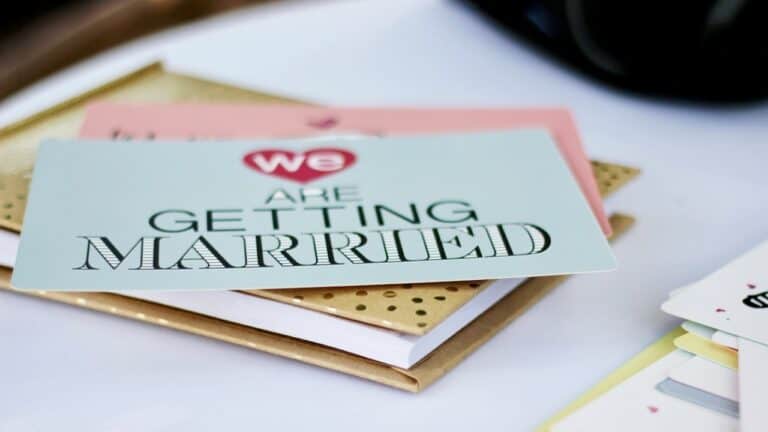 Getting Married invitation card on a stack of papers for engagement party planning.