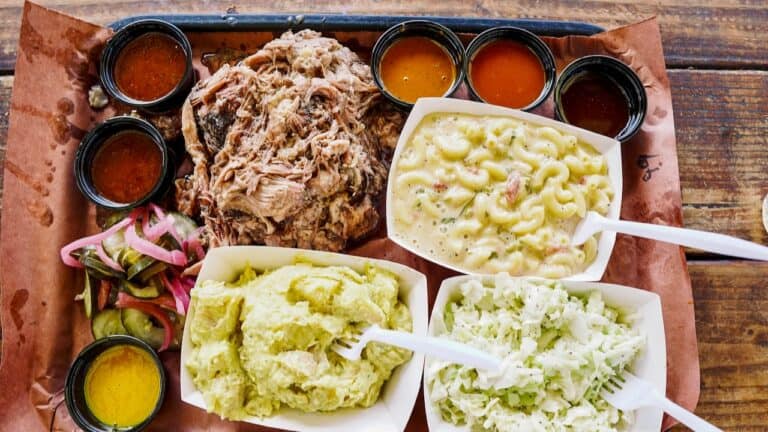 Delicious BBQ platter with pulled pork, mashed potatoes, coleslaw, and sauces.