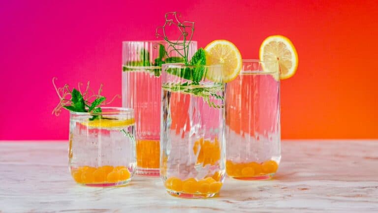 Refreshing non-alcoholic drinks with lemon and mint garnishes on a colorful background.