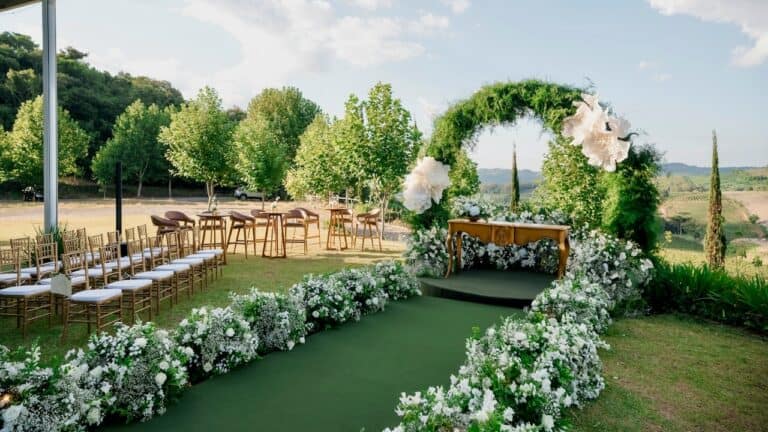 Beautiful outdoor garden party setup with floral arch and seating area.