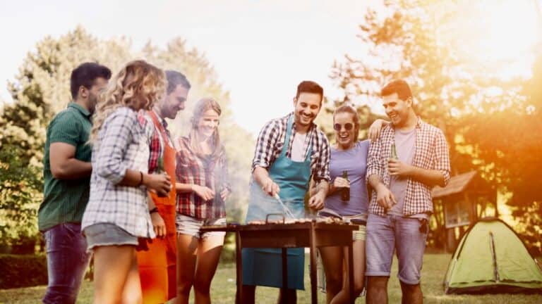 Group of friends enjoying a barbecue outdoors during sunset.