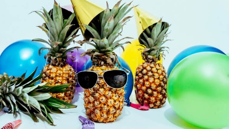 Colorful pineapple party decorations with sunglasses and balloons for celebration.
