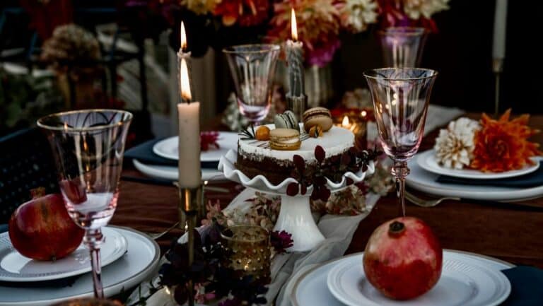 Elegant table setting with candles, flowers, and desserts for a special occasion.
