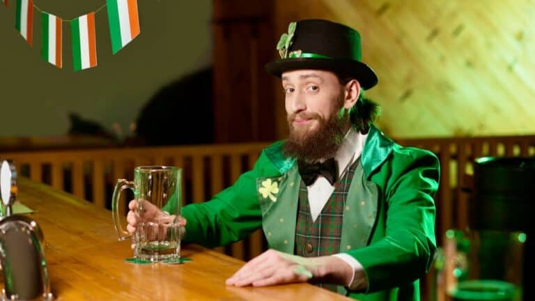 Man dressed as a leprechaun holding a beer mug at St. Patrick's Day celebration.