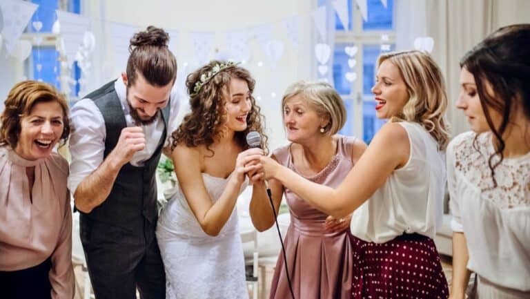 Group of women and a man singing karaoke at a celebration event.