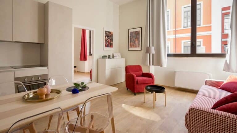 Bright, modern living room with red and pink furniture and large windows.