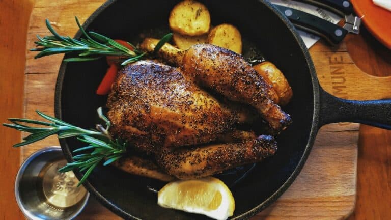 Juicy roasted chicken with herbs and potatoes in a skillet.