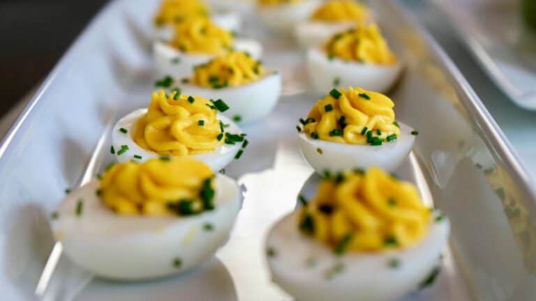 Close-up of deviled eggs garnished with herbs on a tray.