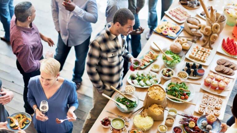 Guests enjoying a buffet with salads, bread, and desserts at a large gathering.