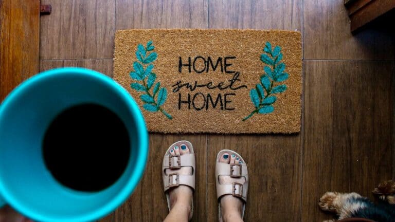 Welcome mat with 'Home Sweet Home' and blue leaf designs at housewarming party.
