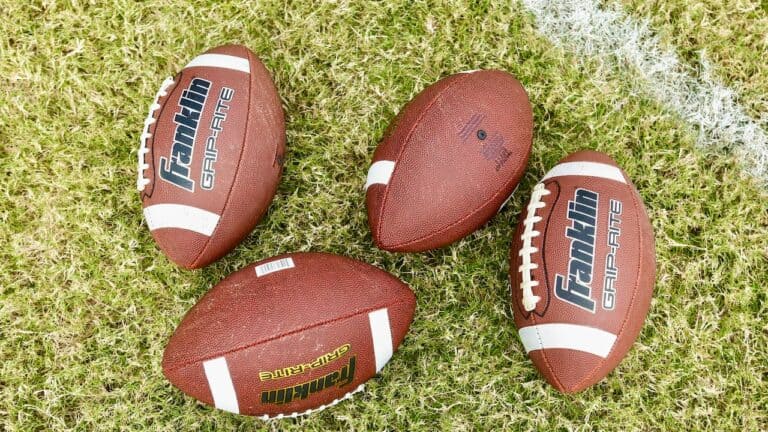 Four footballs on grass for Super Bowl game day celebration.