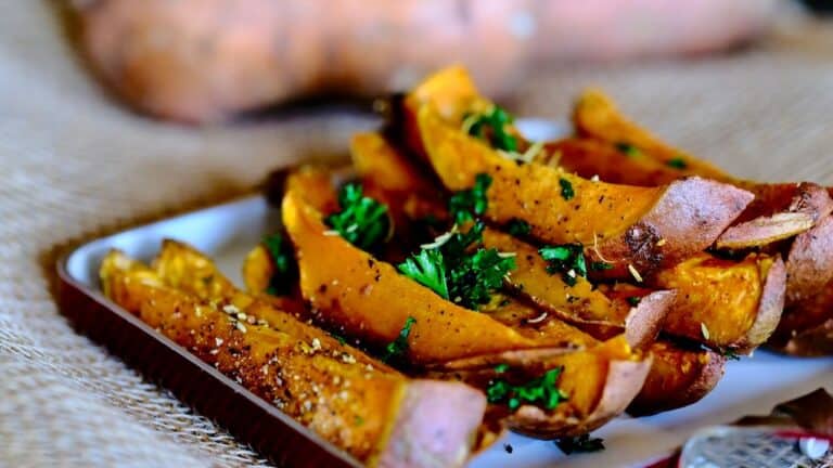 Roasted pumpkin wedges garnished with fresh herbs on a white plate.