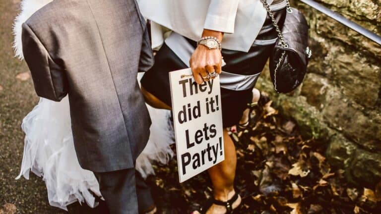 Guests at a bridal shower holding a sign that says "They did it! Lets Party!".