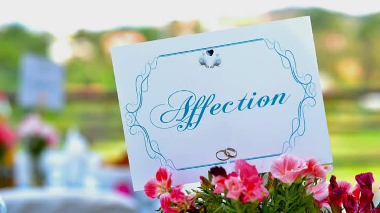 Decorative wedding sign with pink flowers and rings for bridal shower.