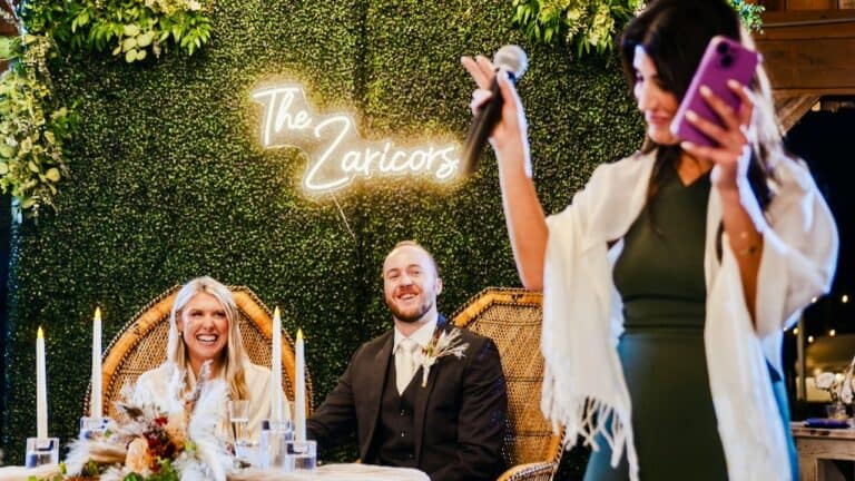 The Zarics couple at their wedding reception with a woman giving a speech.