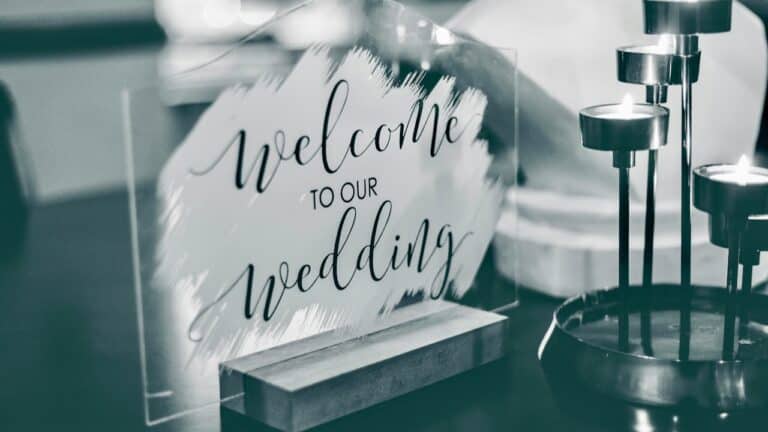 Elegant wedding welcome sign with candles and floral decor.