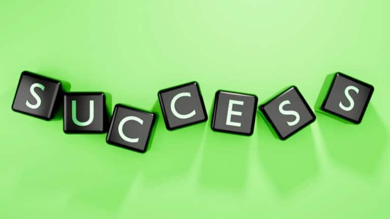 Success spelled out with black letter tiles on a green background.